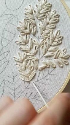 someone is stitching leaves on a piece of fabric