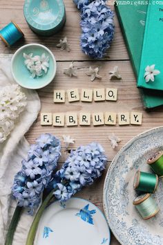 the word hello february spelled with scrabble letters and flowers on plates, napkins, and other items