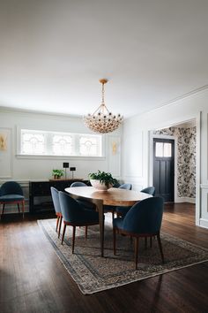 a dining room table with blue chairs and a chandelier hanging from the ceiling