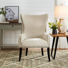 a white chair sitting on top of a rug next to a table with a lamp