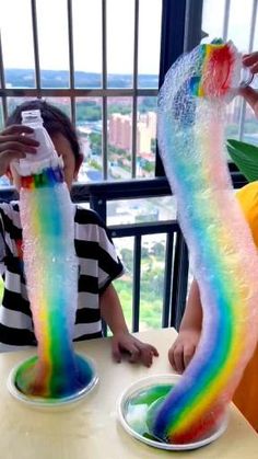 two children sitting at a table covered in fake water and rainbow colored streamers on their feet