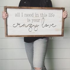 a woman holding up a sign that says, all i need in this life is your crazy love