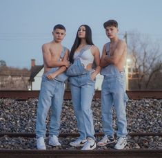 three people standing next to each other on train tracks