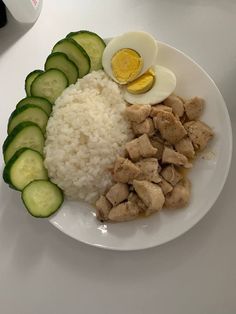 a white plate topped with rice, cucumbers and an egg