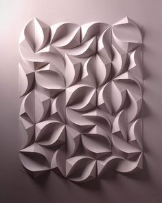 an abstract piece of art made out of white paper on a gray wall with no one in it
