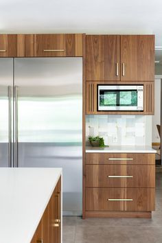a modern kitchen with wooden cabinets and stainless steel refrigerator freezer, along with white counter tops