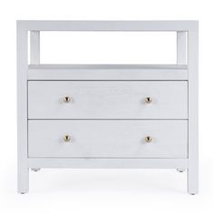 a white dresser with three drawers and two brass knobs on the bottom, against a white background