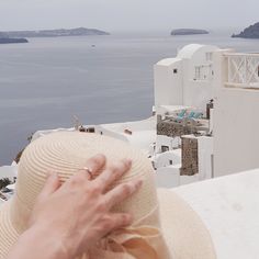 a person's hand on the top of a hat with water in the background