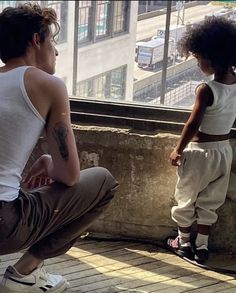 a young boy and an older man sitting on a ledge looking out at the city