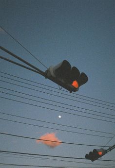 the traffic light is red and there are many power lines in the sky above it