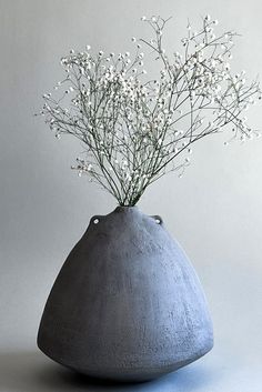 a gray vase with white flowers in it