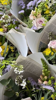 an arrangement of flowers and books laying on top of each other
