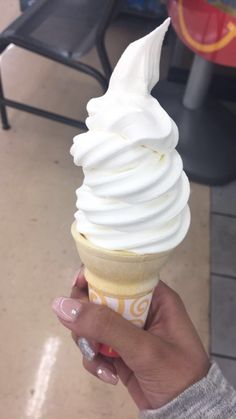 a hand holding an ice cream cone with white icing