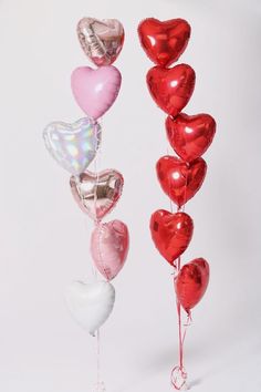 there are many heart shaped balloons in the shape of hearts, and one is tied to a string