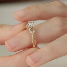 a close up of a person's hand holding a diamond ring