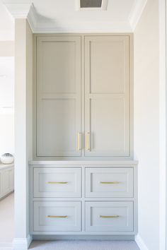 an empty room with white cabinets and drawers