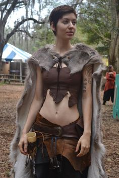 a woman dressed up as a warrior with tattoos on her chest and fur stole around her shoulders