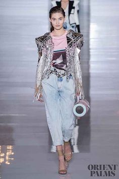 a model walks down the runway in a pink top and jeans