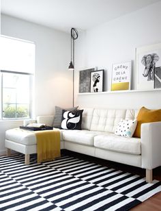 a living room with white furniture and black and white striped rugs on the floor