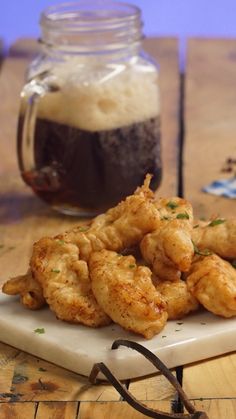 some fried food on a white plate next to a jar of beer and eyeglasses