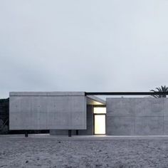 a concrete building with an open door on the side and palm trees in the background