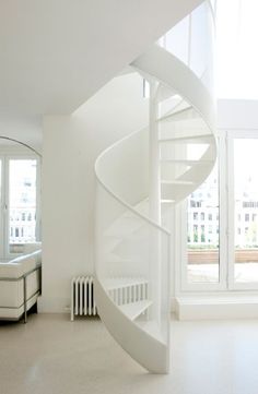 there is a spiral staircase in the middle of this room with white walls and flooring