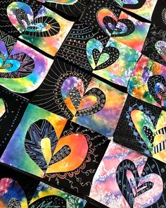 many colorful hearts are arranged together on the table with black and white paper in the background