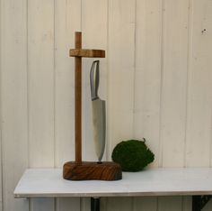 a knife is sitting on top of a wooden stand next to a moss covered rock