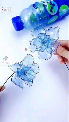someone is drawing flowers on a piece of paper with water bottle next to the flower