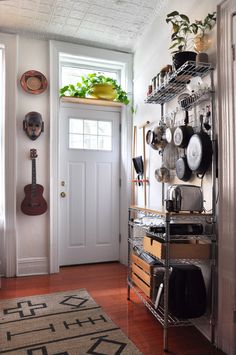 a kitchen area with pots and pans on the wall, shelves holding utensils