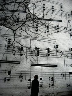 a man standing in front of a wall with musical notes on it