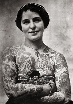 an old photo of a woman with tattoos on her arms