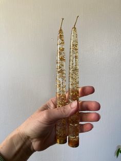 someone holding two gold colored candles in their hand