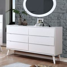 a white dresser with a round mirror on top