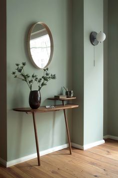a wooden table with a mirror and vase on it