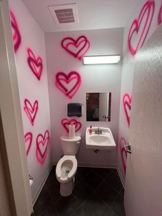 a bathroom with pink hearts painted on the wall next to a white toilet and sink