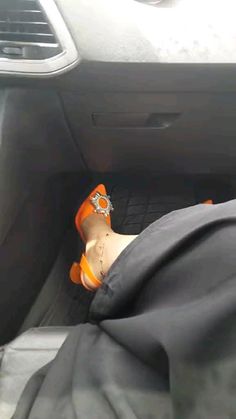 a person wearing orange shoes sitting in the back seat of a car