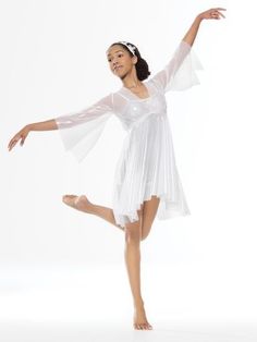 a young woman in a white dress is dancing with her arms out and legs spread wide