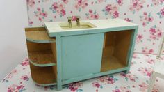 a dollhouse bathroom with pink flowers on the wall and blue sink in the cabinet