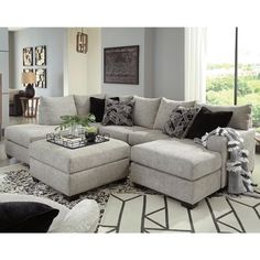 a living room scene with focus on the sectional sofa and footstool in the center