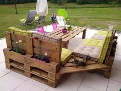 an outdoor table made out of wooden pallets with cushions and pillows on the top
