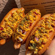 two hot dogs covered in cheese and toppings