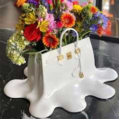 a white purse with flowers in it sitting on a table