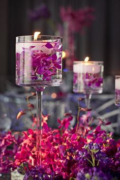 purple flowers and candles are in glass vases