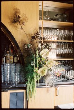 flowers and wine glasses are sitting on the counter in front of an empty glass case