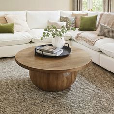 a living room with white couches and a wooden coffee table in the center area