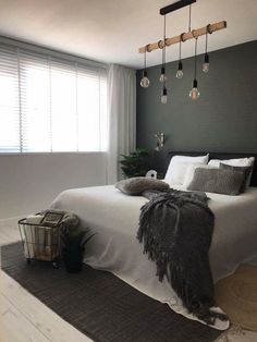 a bedroom with grey walls, white bedding and black accents on the headboard