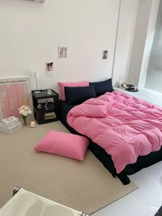 a bed with pink sheets and black pillows