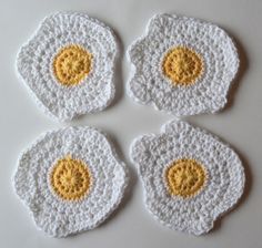 four crocheted coasters with yellow and white eggs on them