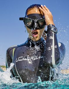 a man in a wet suit and goggles standing in the water with his hands on his head